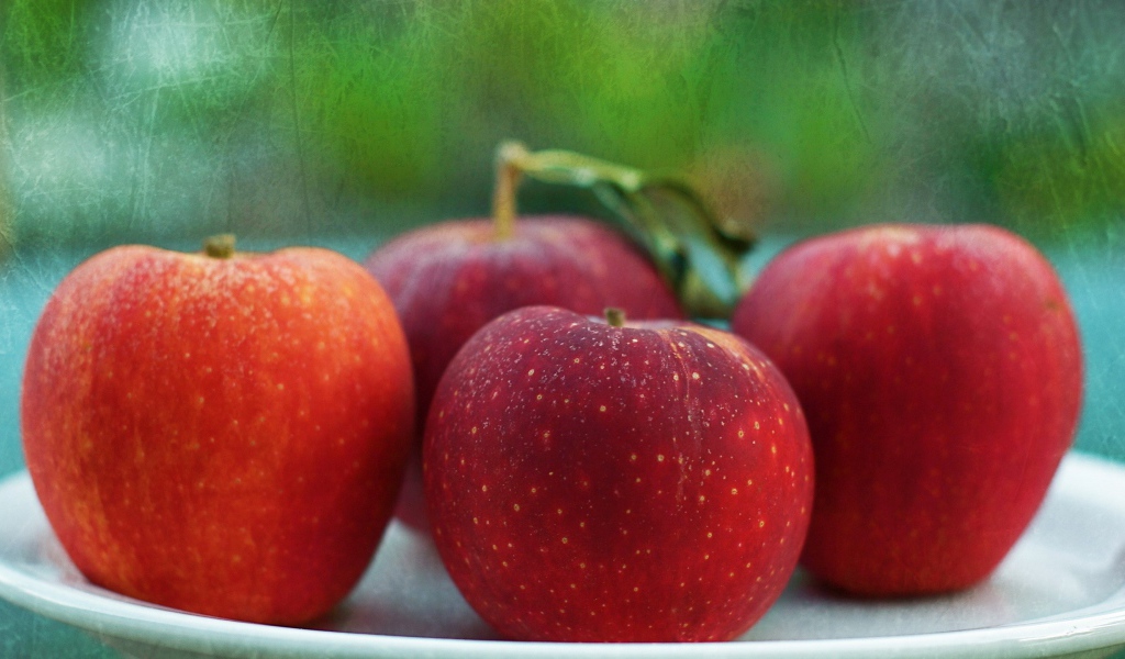 Четыре красных яблока на тарелке