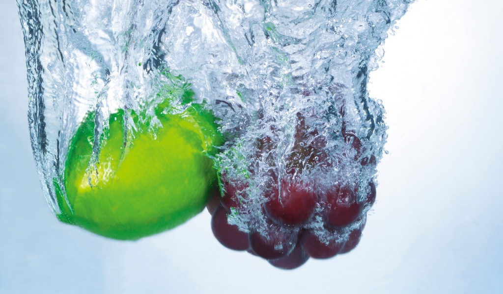 Зеленый лимон и кисть винограда в воде