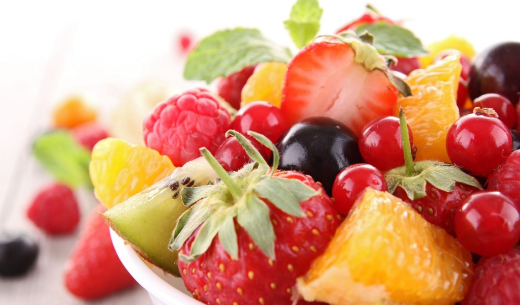 Кусочки спелых фруктов и ягоды на тарелке