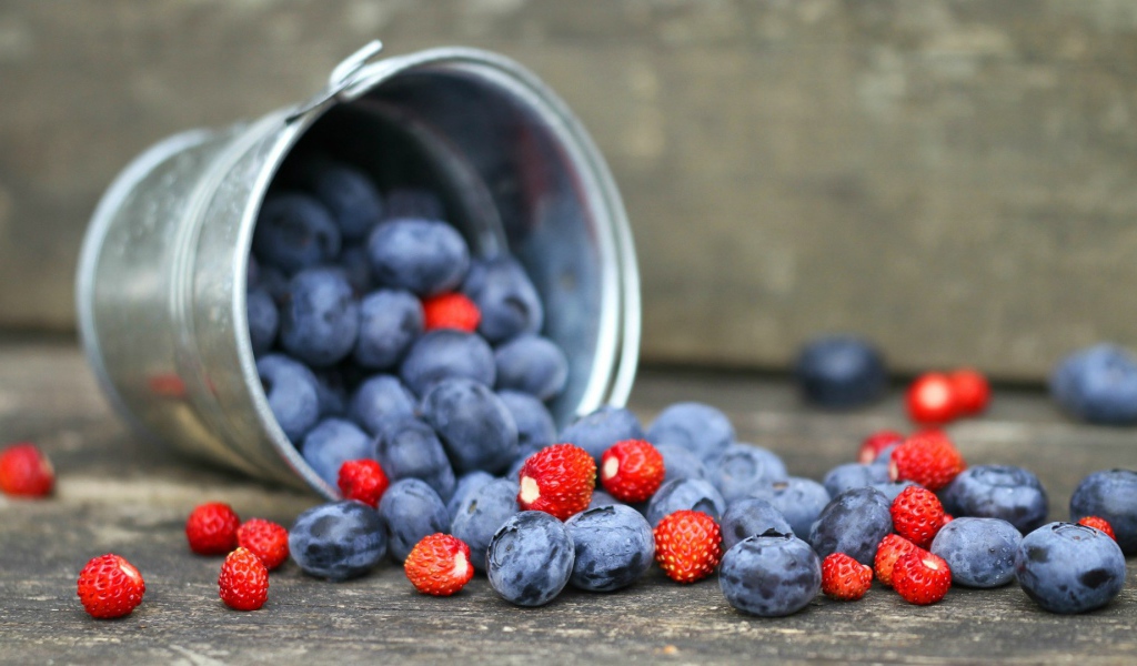 Плоды клубники и сливы в ведре