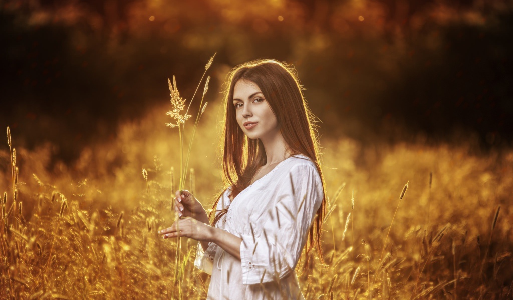 Девушка в белом платье держит в руке колоски