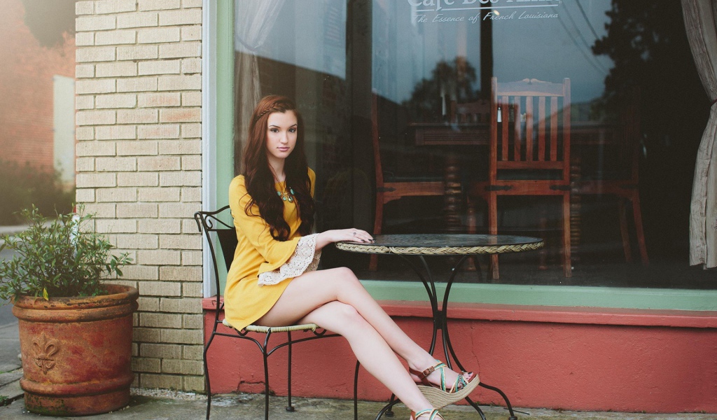 Девушка сидит за столиком уличного кафе