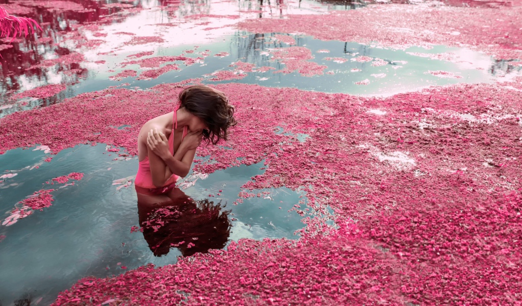 Девушка стоит в воде среди розовых лепестков