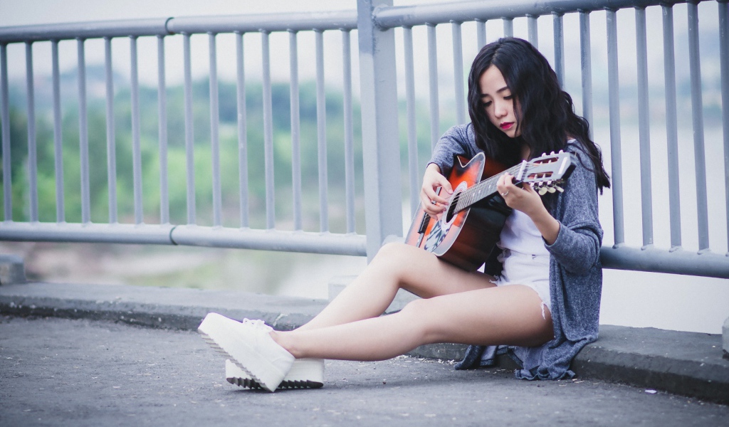 Азиатка брюнетка с гитарой на мосту