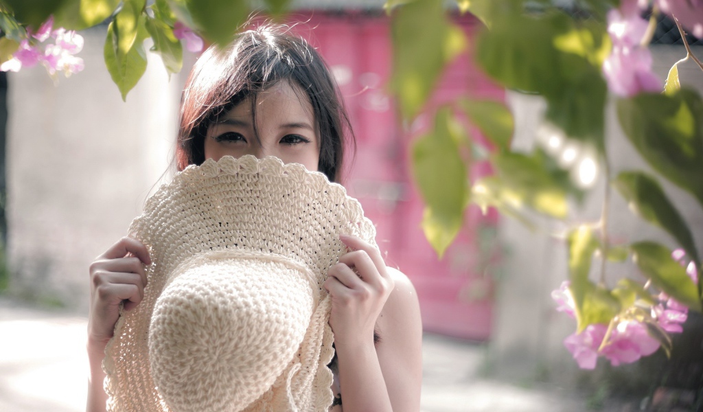 Азиатская девушка прикрыла лицо шляпой