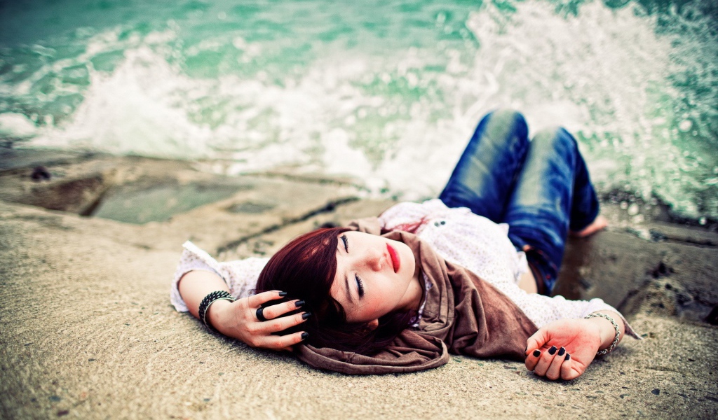 Босая девушка в джинсах лежит на набережной