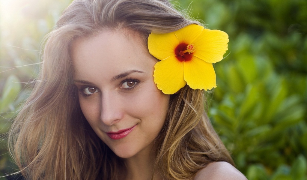 Большой желтый цветок в волосах у девушки