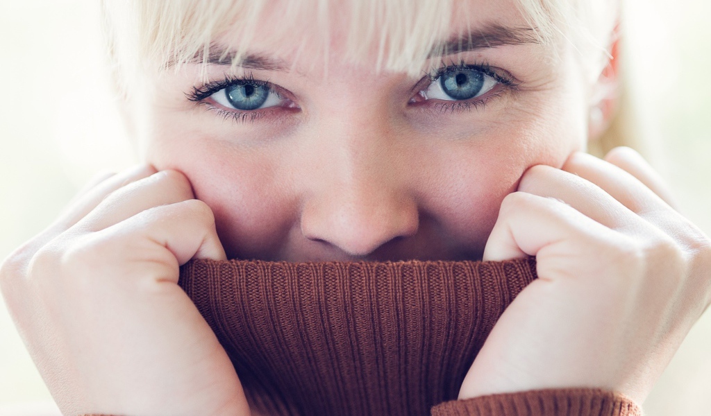 Блондинка прячет лицо в вороте свитера