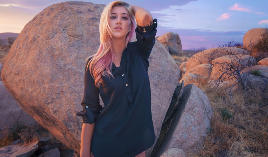 Блондинка стоит у большого валуна