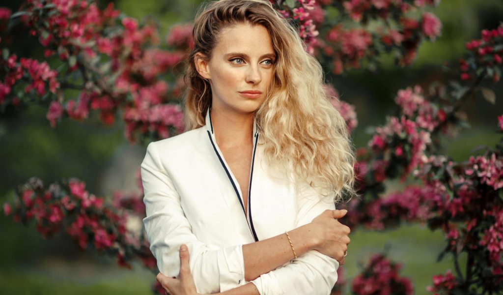 Голубоглазая блондинка на фоне цветущих деревьев