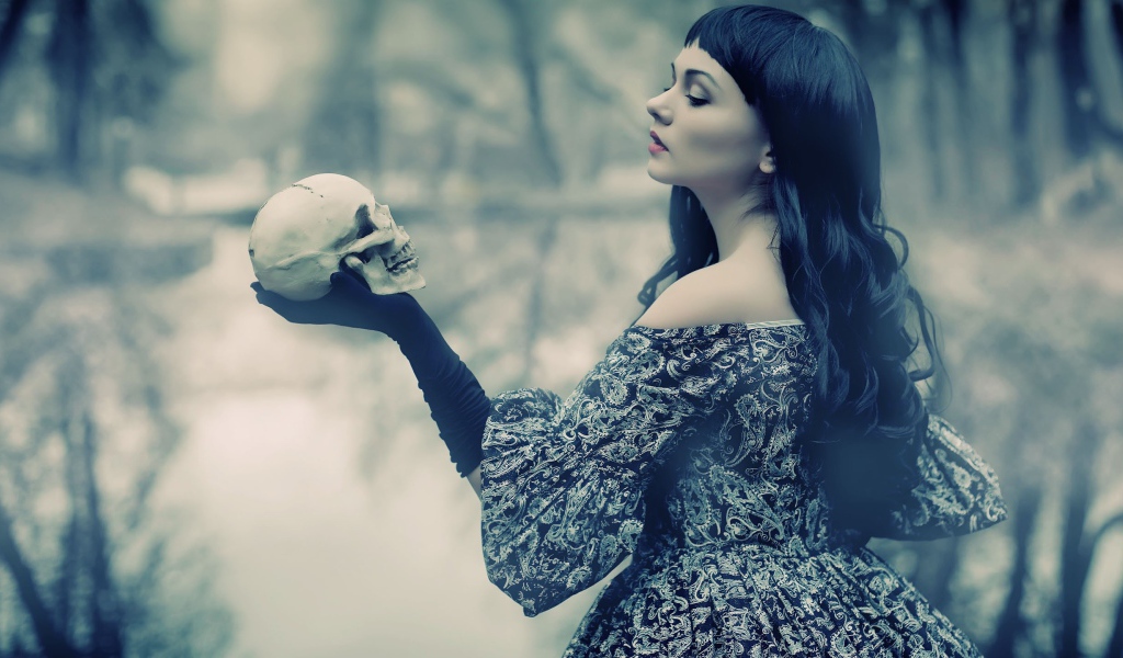 Брюнетка держит в руке череп