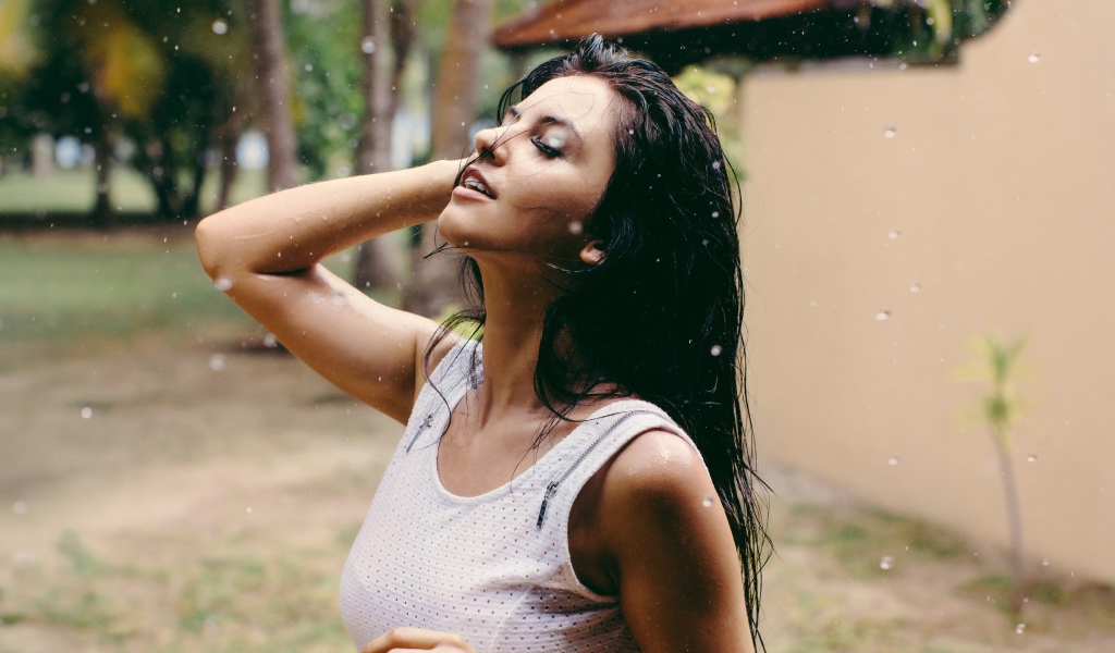 Брюнетка подставляет лицо под капли дождя
