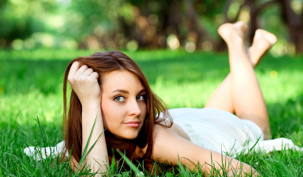 Беззаботная девушка лежит на зеленой траве
