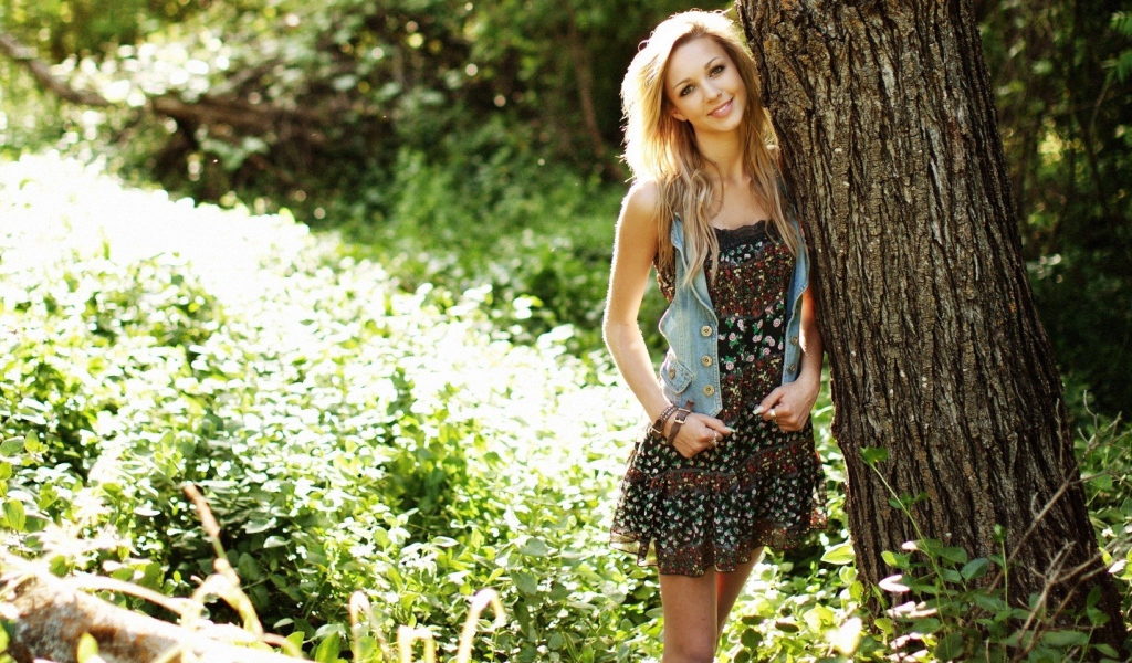 Милая блондинка прислонилась к дереву