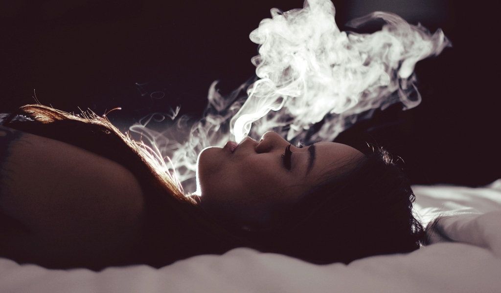 Девушка выпускает дым изо рта