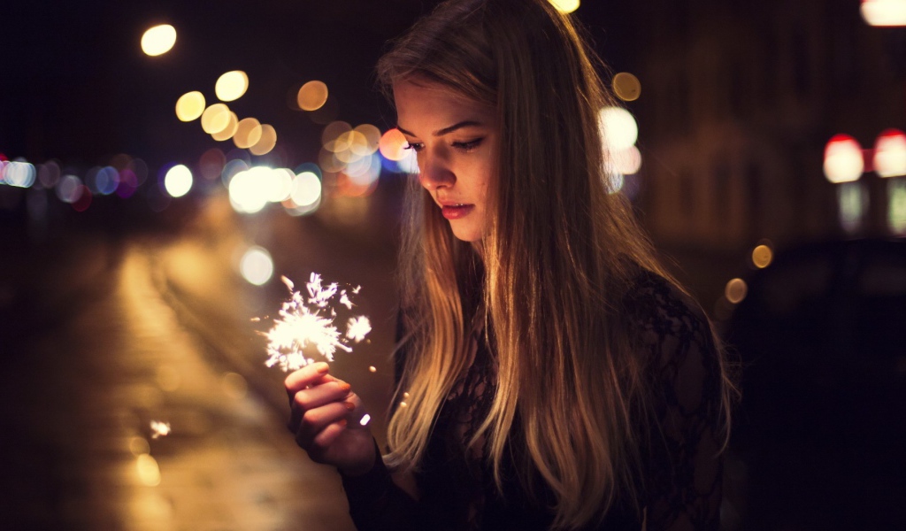 Девушка держит в руке бенгальский огонь