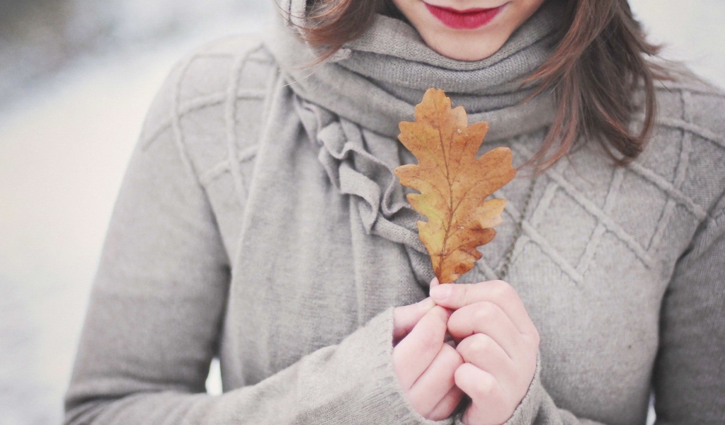 Девушка держит в руках желтый лист