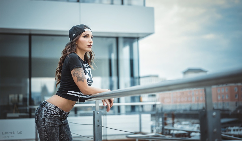 Девушка в кепке с тату смотрит на порт