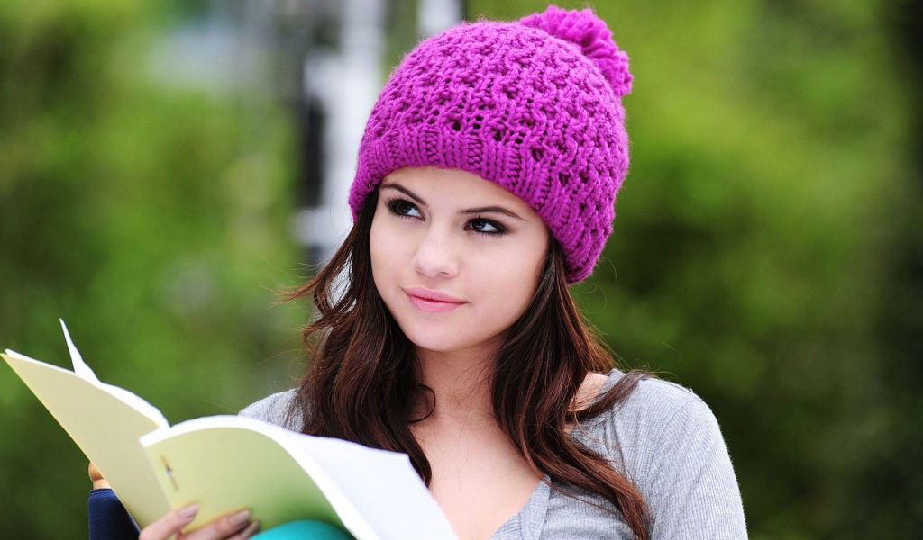 Девушка в сиреневой шапке читает книгу