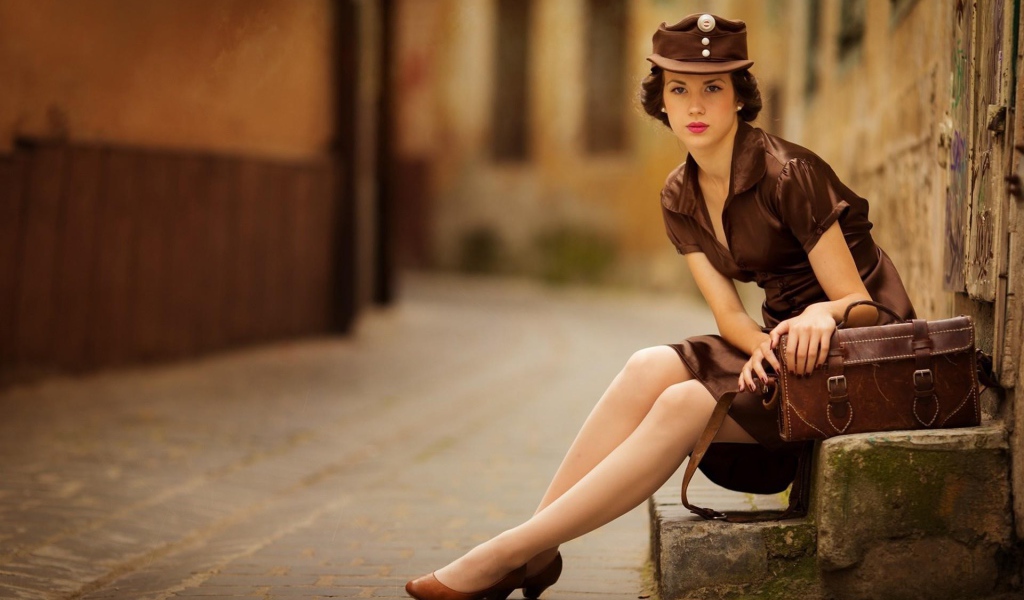 Девушка в коричневой одежде сидит у дороги