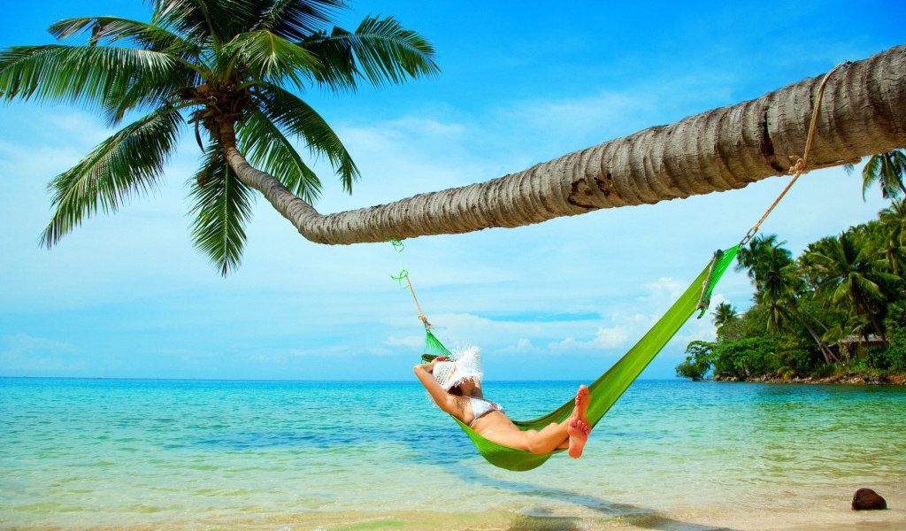 Девушка в зеленом гамаке под пальмой