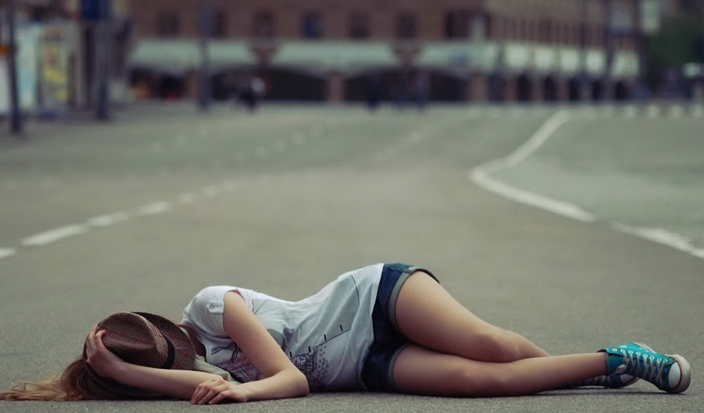 Девушка в шляпе лежит на дороге