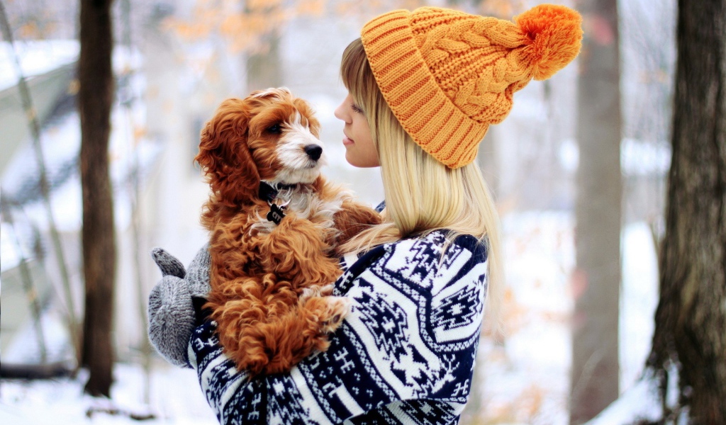 Девушка в оранжевой шапке держит на руках собаку