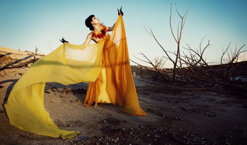 Девушка в оранжевом позирует в пустыне