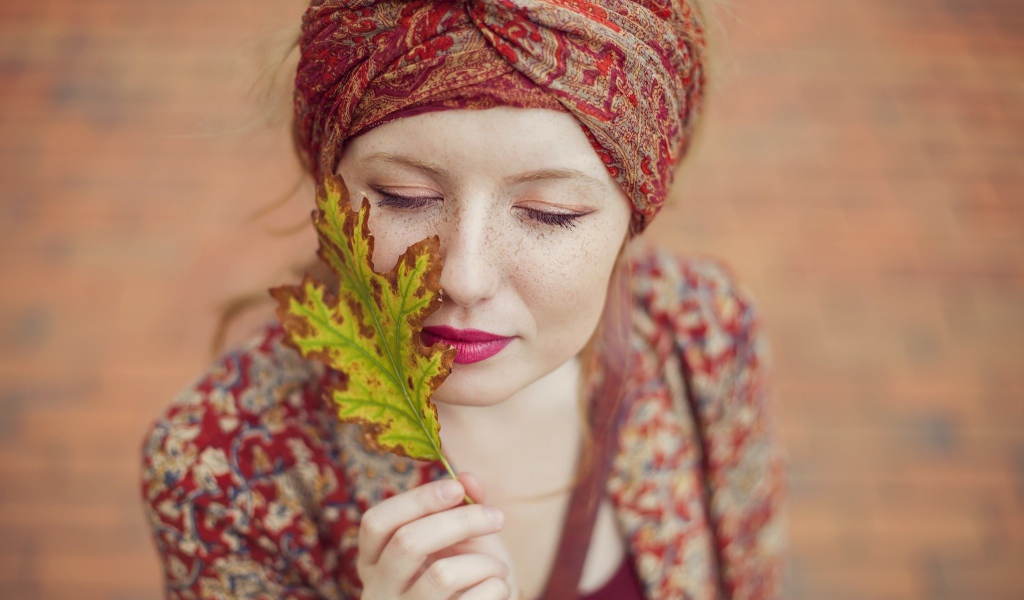 Девушка в традиционном наряде держит в руке лист
