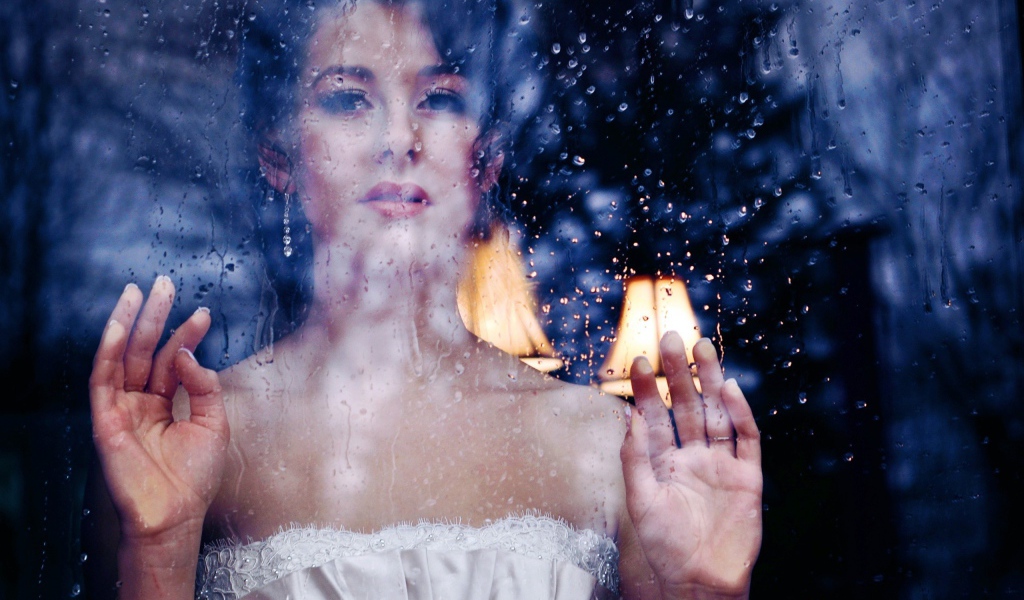 Девушка в белом платье за мокрым стеклом
