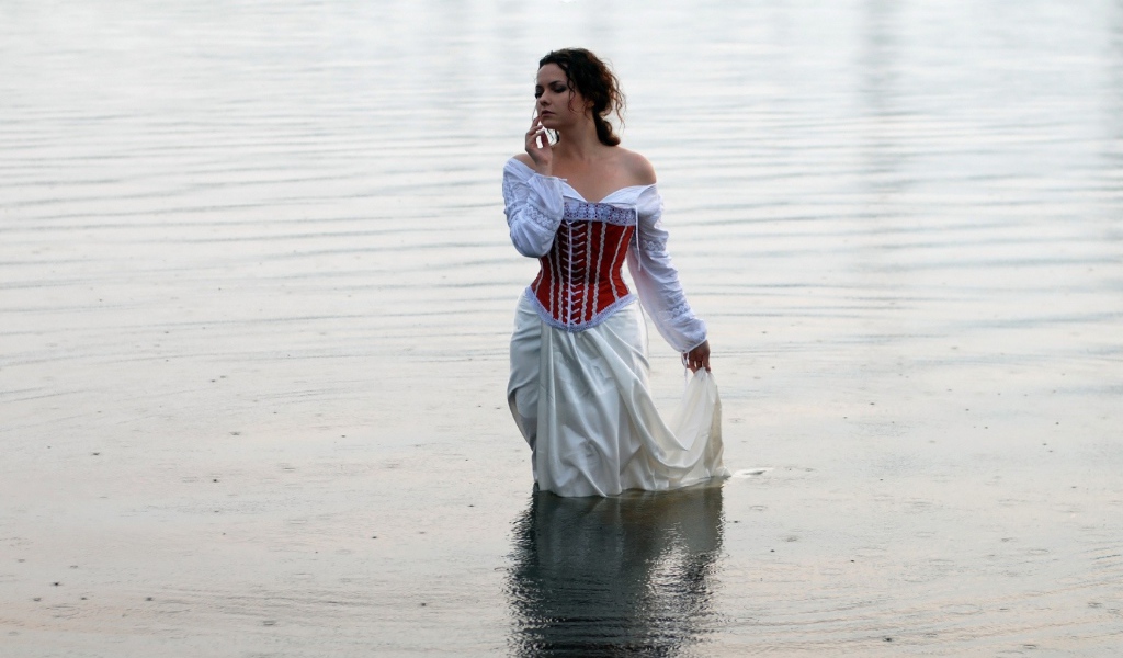 Девушка в белом платье стоит в воде