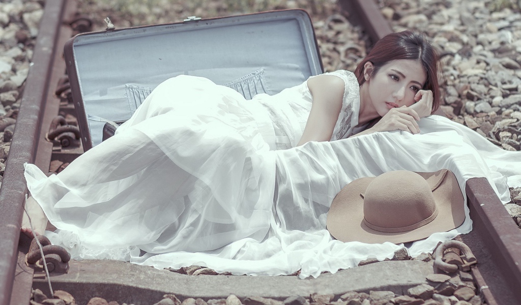 Девушка лежит в чемодане на рельсах