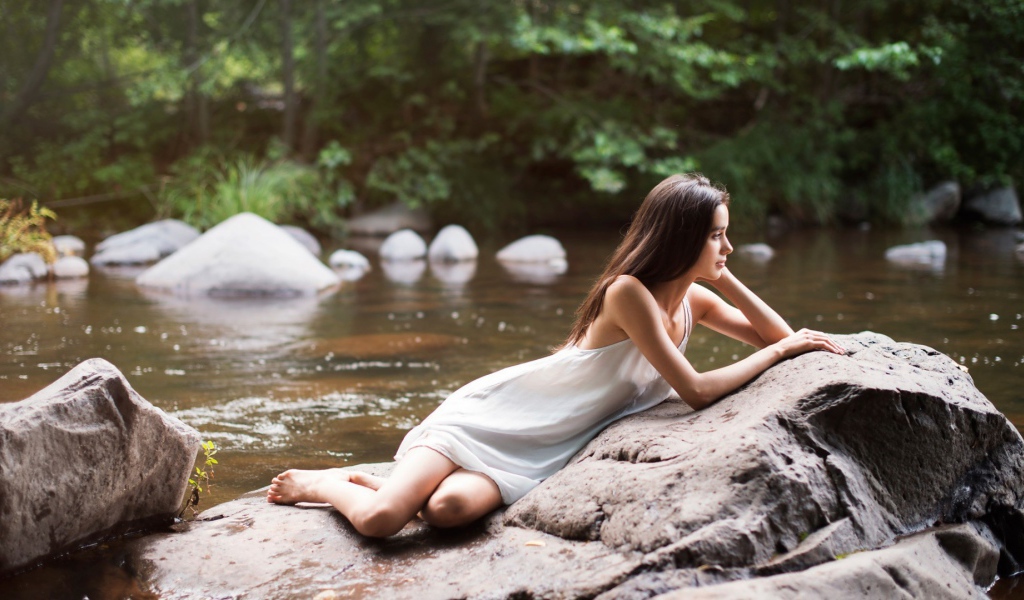 Девушка лежит на камне у реки