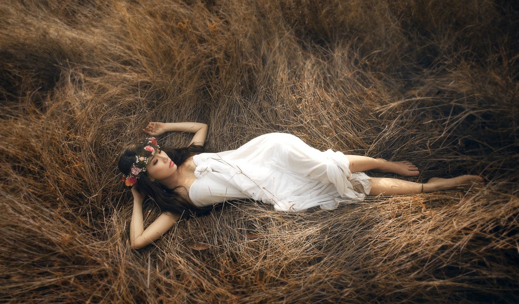 Девушка лежит на сухой траве