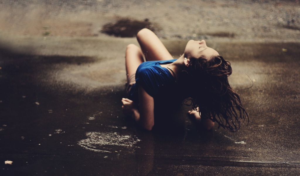 Девушка лежит на асфальте под дождем