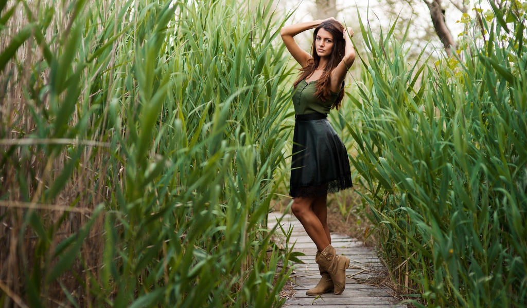 Девушка на деревянной дорожке среди камышей