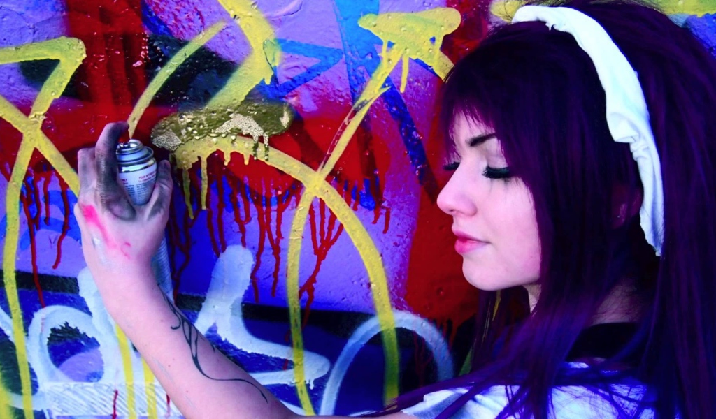 Девушка рисует граффити на стене