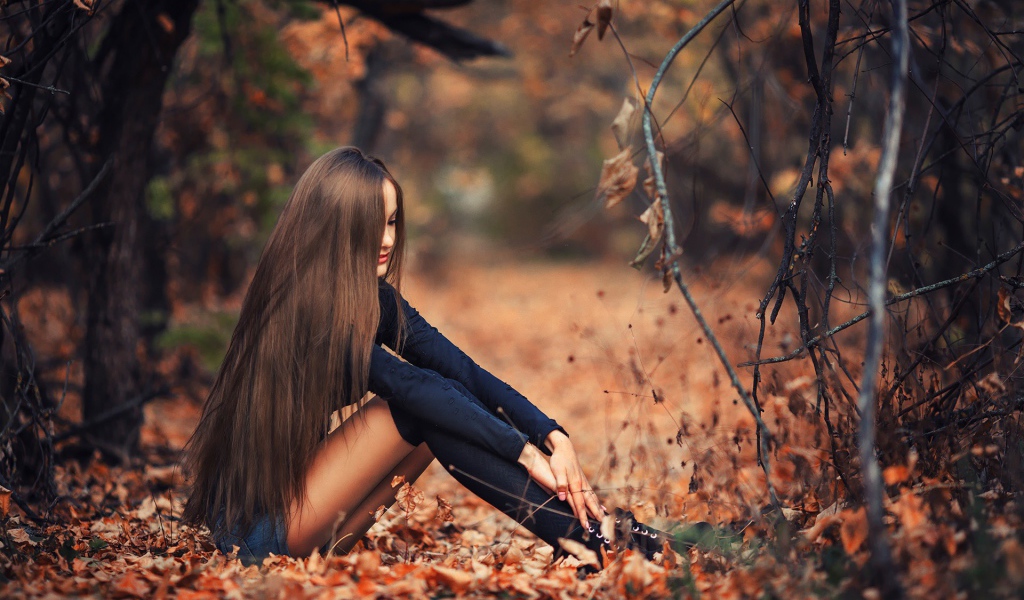 Девушка сидит на осенней листве