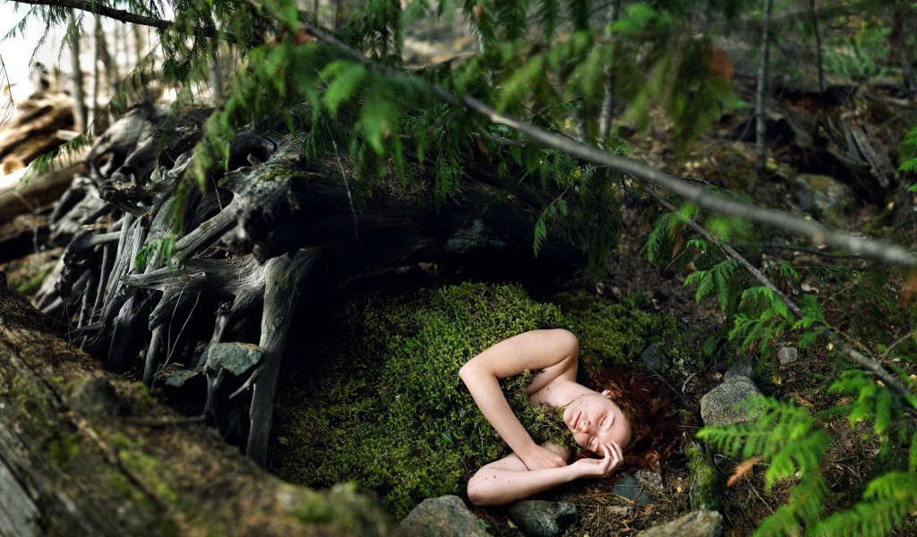 Девушка спит укрывшись мхом в лесу