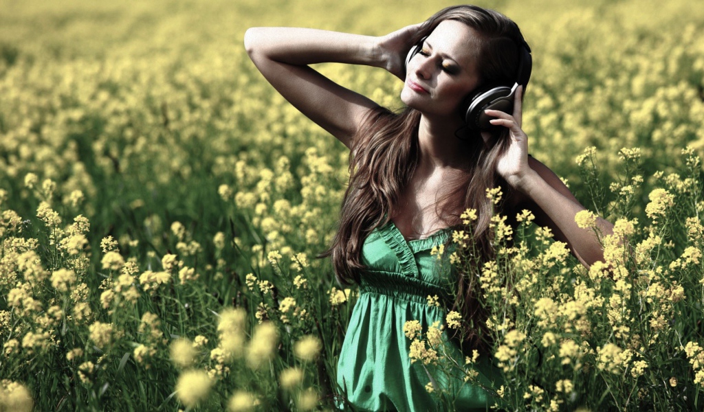 Девушка стоит среди цветов в наушниках