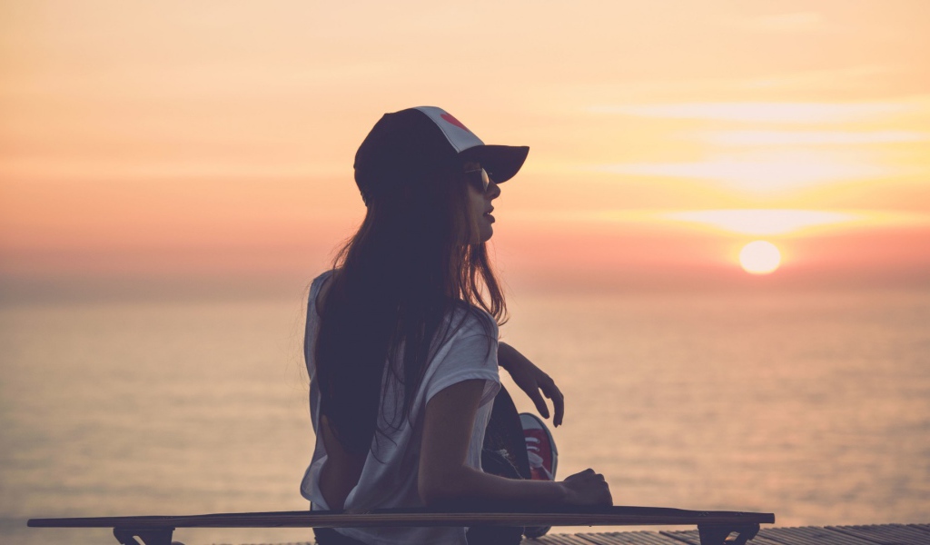 Девушка смотрит на закат на пляже