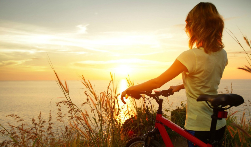 Девушка с велосипедом смотрит на закат