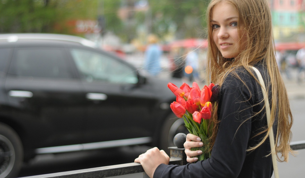 Девушка с букетом тюльпанов стоит у забора