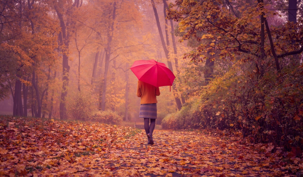 Девушка с красным зонтом идет по аллее