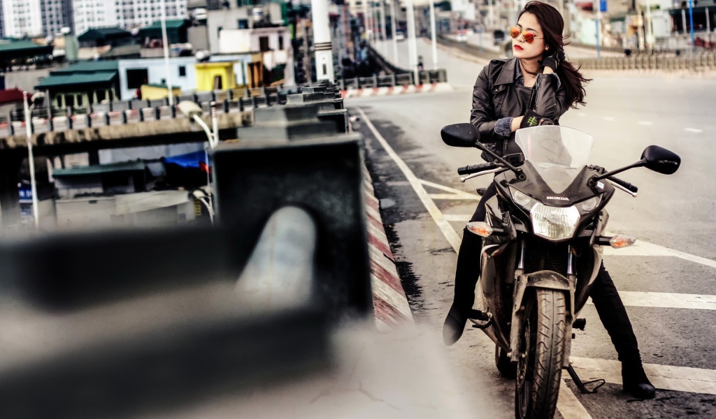 Девушка в темных очках сидит на мотоцикле
