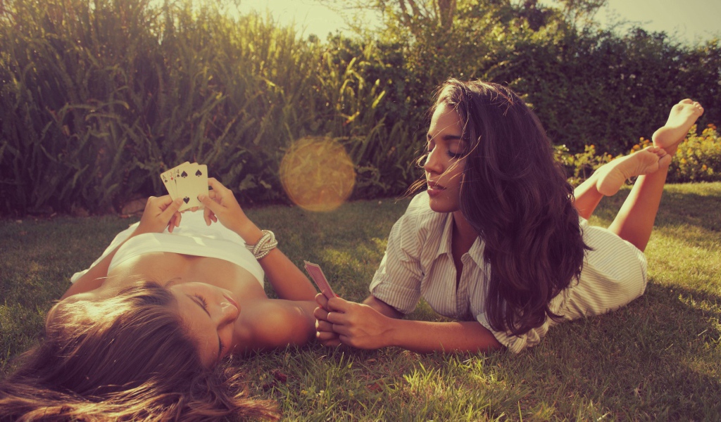 Девушки играют в карты на газоне