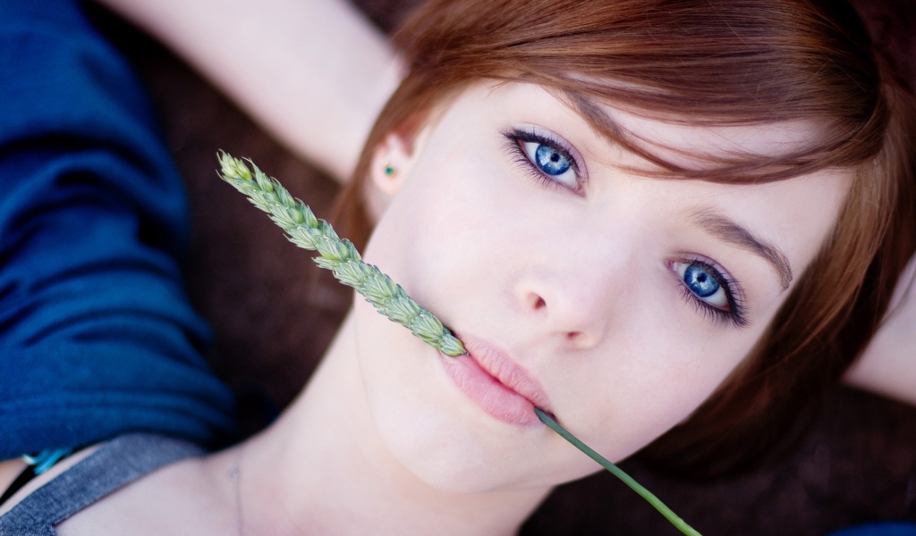 Зеленый колосок во рту у девушки