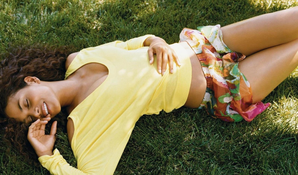 Мулатка в желтой футболке лежит на траве