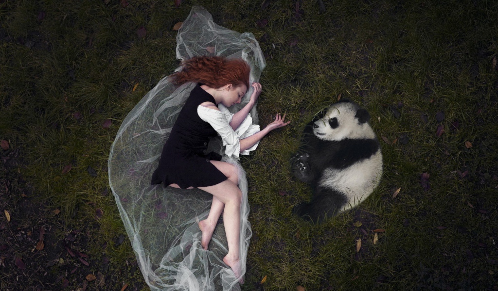 Девушка и панда лежат рядом на траве