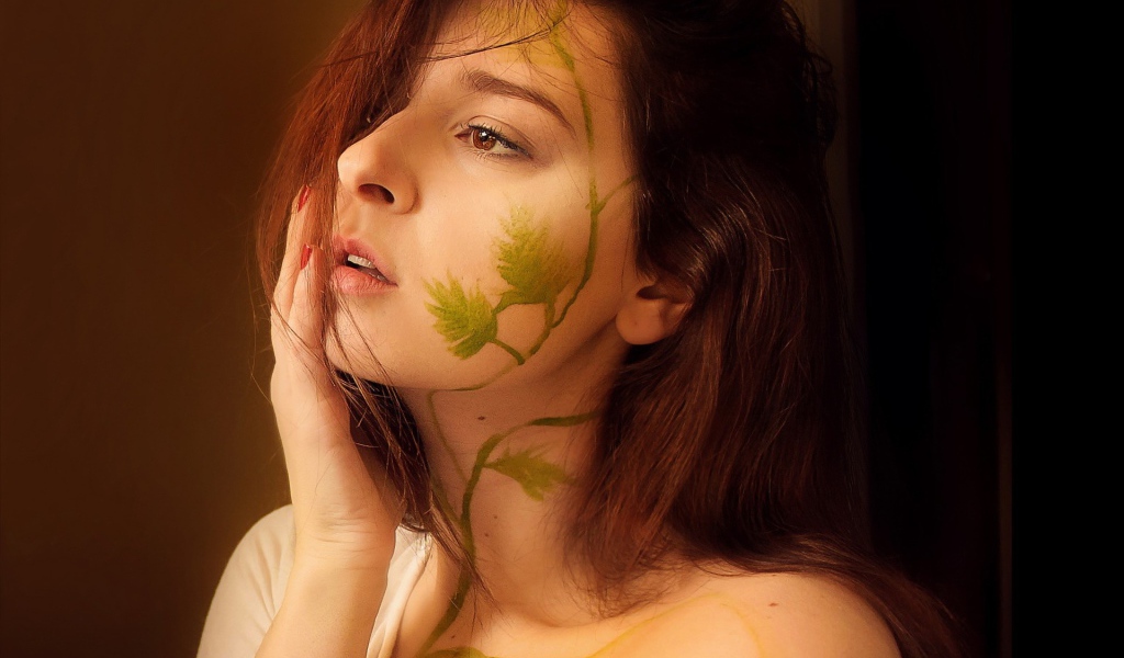Рисунок зеленых листьев на лице и шее девушки